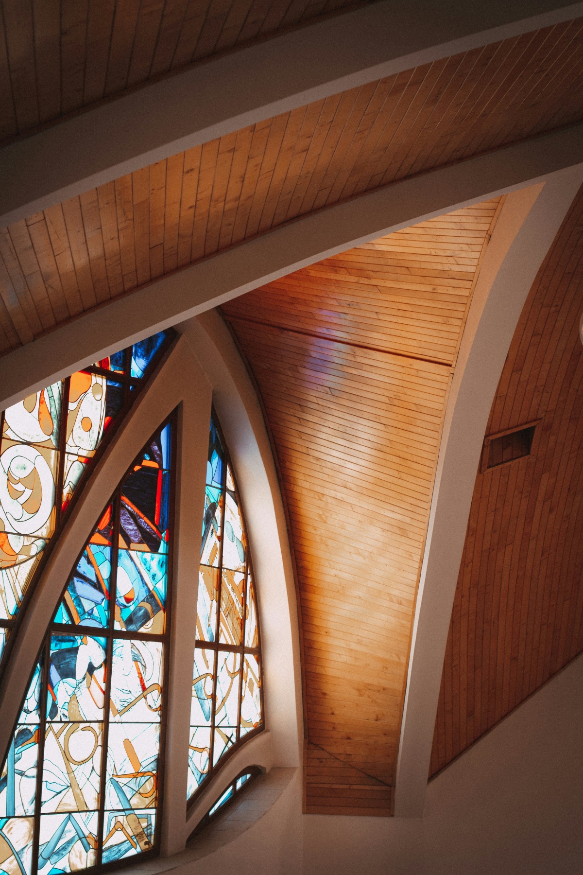 Sunlight through a stained-glass window and timber-vaulted sanctuary ceiling